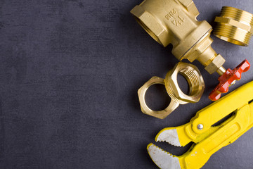 Wrench, working gloves and brass fittings on crude floor background. 