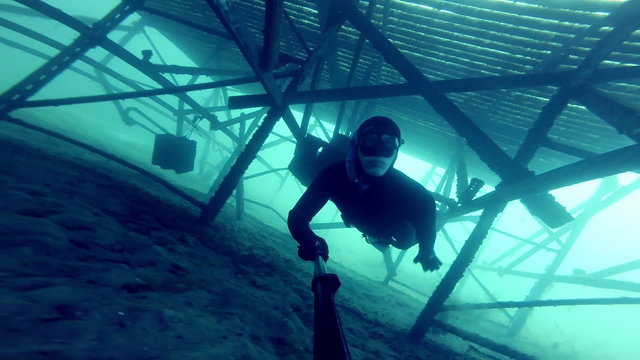 Freediver Exploring a Big Underwater Metalic Structure