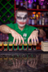 Bartender with make-up for Halloween proposes shot cocktail
