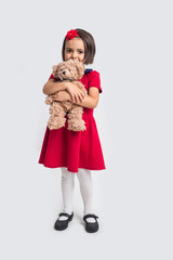 Beautiful little girl in a red dress with a toy bear