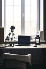 Workplace with open laptop with black screen  on modern wooden desk, angled notebook on table in home interior, filtered image.
Photographer, camera