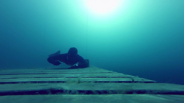 Freediving is fun ! Freediver crawling Underwater on a Wood Platform