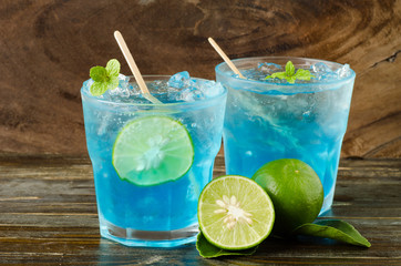 Ice blue drink with lemon on wooden background