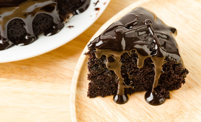 Piece of dark chocolate cake on wooden plate
