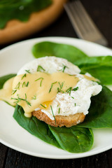 Poached egg on a piece of bread with spinach on the wooden table