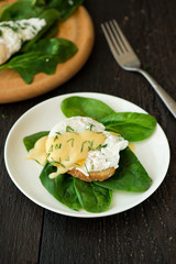 Poached egg on a piece of bread with spinach on the wooden table