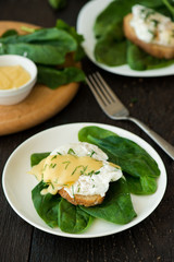 Poached egg on a piece of bread with spinach on the wooden table
