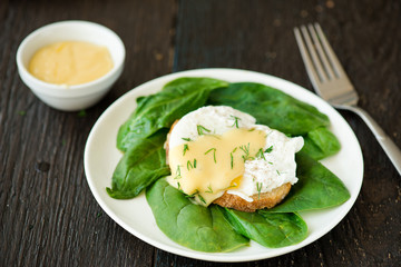Poached egg on a piece of bread with spinach on the wooden table