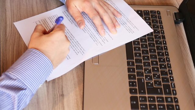 mani di uomo che firmano il contratto di lavoro con la benna su scrivani di ufficio