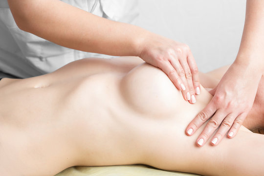 Beauty young woman recieving breast massage at spa. masseur's hands on the woman's breast