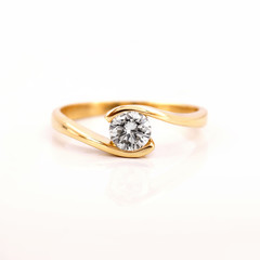 Gold engagement ring with a diamond on a white background - obrazy, fototapety, plakaty
