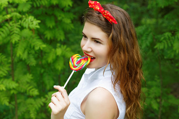 girl with a lollipop in the trees in the summer