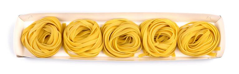 Italian rolled uncooked fettuccine in an open cardboard box isolated on a white background.