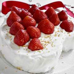 cake covered with cream and topped with strawberries