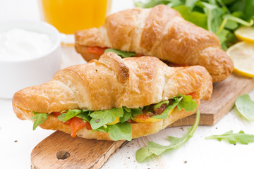 fresh croissant stuffed with fish and arugula for breakfast