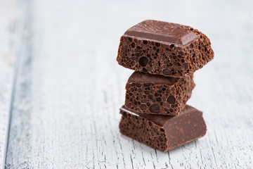 Porous dark chocolate on a white wooden background