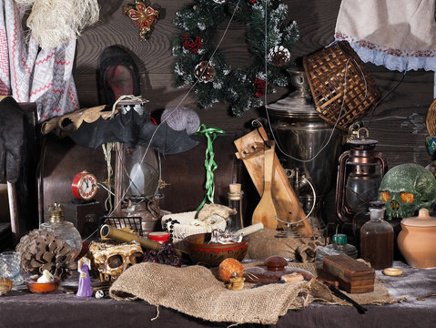 На старом пыльном чердаке. Множество разных старых предметов - часы будильник, керосиновые лампы, самовар, сломанные игрушки, коробки и шкатулки, черепа, нитки. Новогодний венок и старые туфли.