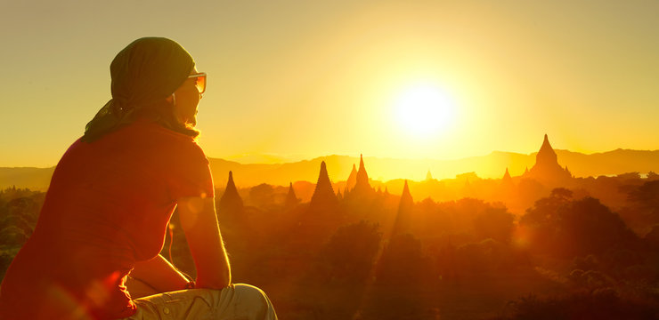 female traveler watching sunset over ancient temples at Bagan, Myanmar. 