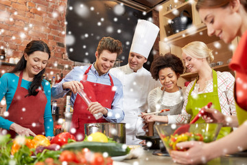 happy friends and chef cook cooking in kitchen