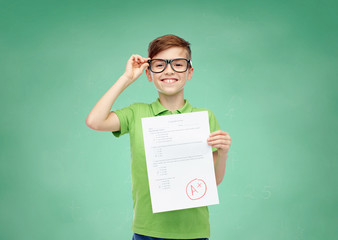 happy boy in eyeglasses holding school test result