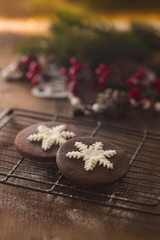 Fototapeta na wymiar due biscotti di natale al cacao, primo piano con decori natalizi sullo sfondo