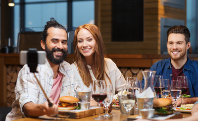 friends taking selfie by smartphone at restaurant