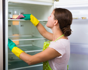 Woman washing fridge at home.