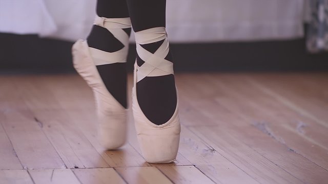 Close up of a ballet dancer walking across a studio floor in pointe shoes