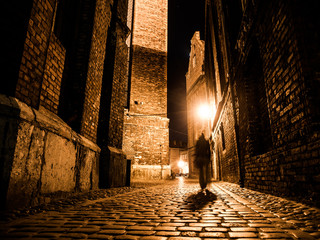 Illuminated cobbled street in old city by night