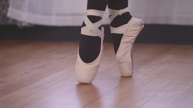 Close up of a ballet dancer walking across a studio floor in pointe shoes