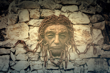 Fototapeta na wymiar Sculpture of man with chains in the wall, Georgia