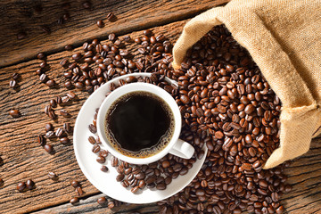 Cup of coffee and coffee beans on old wooden table