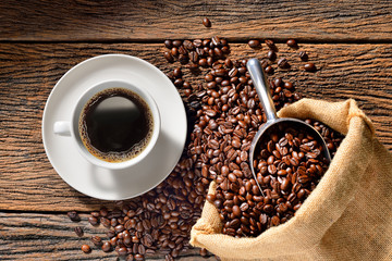 Cup of coffee and coffee beans on old wooden table