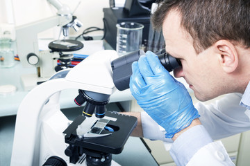 Scientist looking through microscope in laboratory