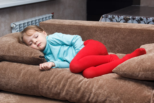 little girl sleeps like a top on couch