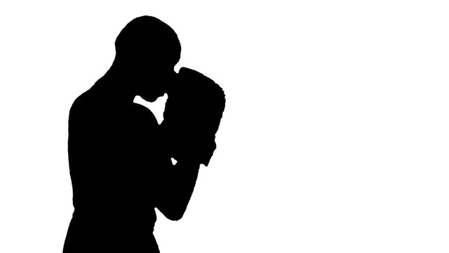 HD silhouette footage of a bald man wearing boxing gloves throwing various punches.