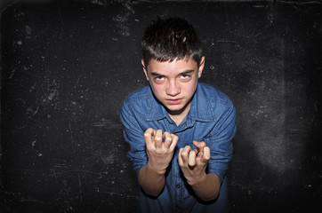 Aggressive boy. Bad caucasian teenager inviting to fight on a dark black-gray background.