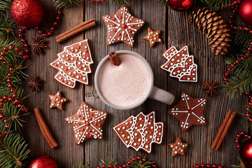 Cup of hot chocolate or cocoa with gingerbread cookies composition in new year decoration frame on vintage wooden table background. Homemade traditional recipe