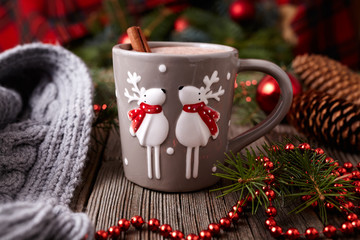 Cup of hot chocolate or cocoa with two cute deer and cinnamon in new year tree decorations frame on...