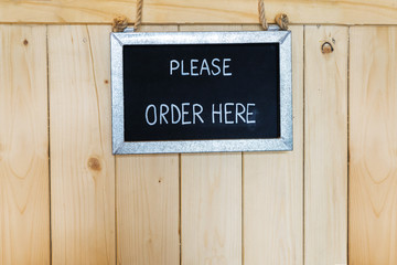 Order here sign hanging on wooden background
