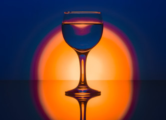 water glass with reflection on blue and orange background