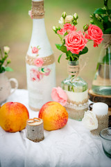 Wedding decor with wedding rings,  and peaches, bottles and candles  in style of a shabby chic. Decoration of a wedding photoshoot.  Details of a wedding decor.