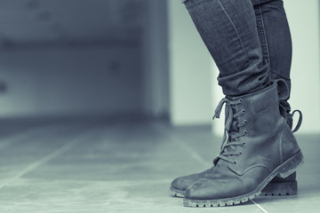 Young fashion man's legs in jeans and brown boots on the floor ,make it a green tone