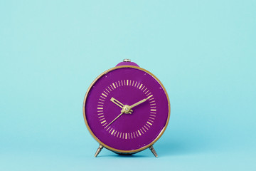 Old purple clock on blue background still life