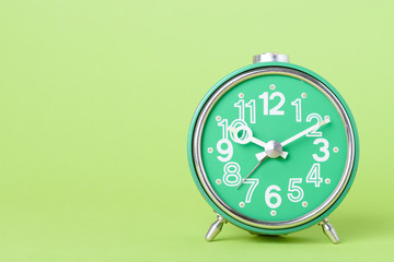 Old retro clock on green background with copy space