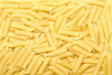 Raw pasta (penne and rigatoni mix) light yellow backdrop