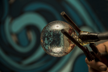 Handmade figure of melted glass, a glass blower working molten glass on a rod 