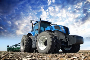 Fotobehang Tractor Blauwe tractor aan het werk op de boerderij
