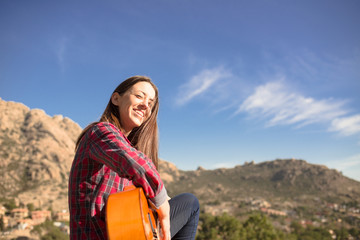 Naklejka premium Smiling Woman sitting on a Rock with her Guitar in Madrid