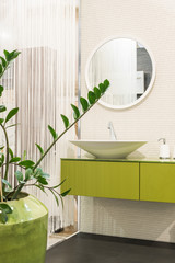 Green and white bathroom interior with sink and round shape mirror and